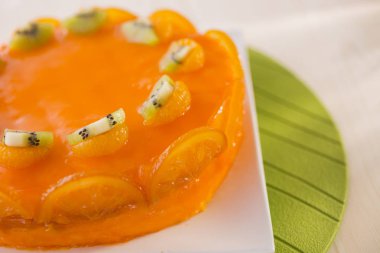 kivi ve beyaz tabakta portakal dilimleri ile dekore edilmiş turuncu kek