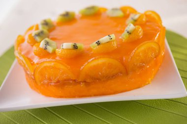 kivi ve beyaz tabakta portakal dilimleri ile dekore edilmiş turuncu kek