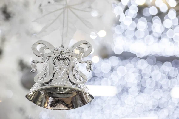 silver christmas bell decoration on blurred sparkling holiday background