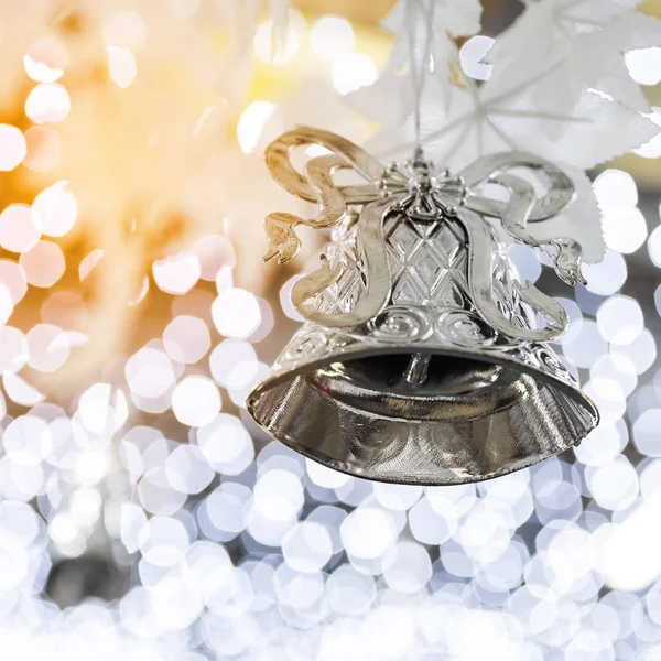 silver christmas bell decoration on blurred sparkling holiday background