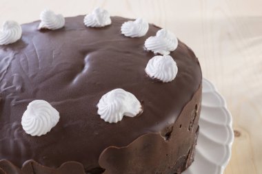 ahşap arka plan üzerinde beyaz plaka üzerinde beyaz meringues ile çikolatalı kek dekore