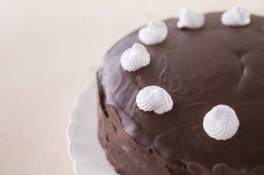 ahşap arka plan üzerinde beyaz plaka üzerinde beyaz meringues ile çikolatalı kek dekore