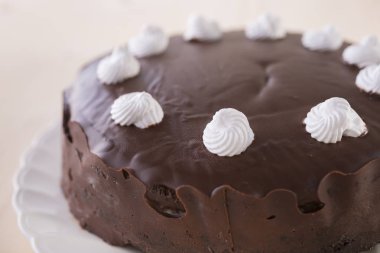 ahşap arka plan üzerinde beyaz plaka üzerinde beyaz meringues ile çikolatalı kek dekore