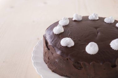 ahşap arka plan üzerinde beyaz plaka üzerinde beyaz meringues ile çikolatalı kek dekore