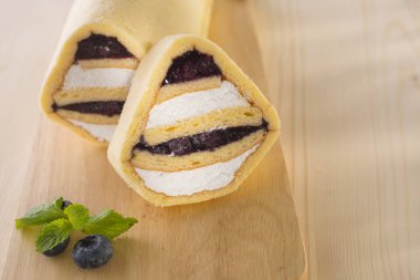 Böğürtlenli rulo pasta üzerinde ahşap arka plan doldurarak krema ile