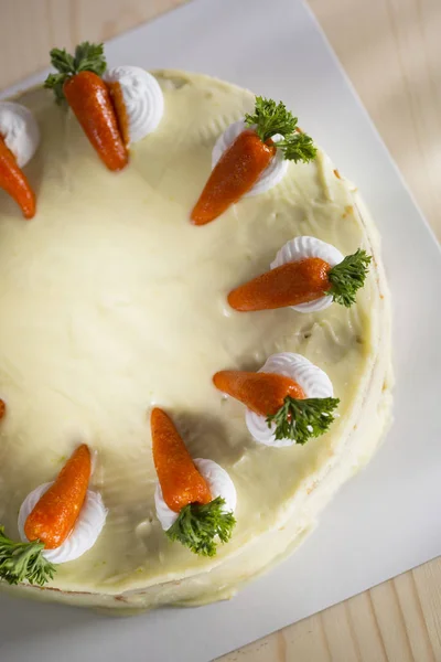 top view carrot cake decorated with miniature carrots on white tray