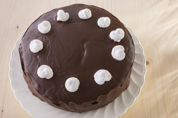 Шоколадный Торт Украшен Белыми Безе Белой Тарелке Деревянном Фоне — стоковое фото