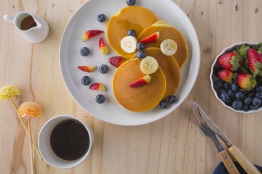 Çilek, muz ve beyaz tabakta bal ile iştah açıcı krep