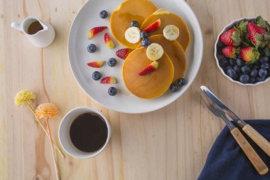 Çilek, muz ve beyaz tabakta bal ile iştah açıcı krep