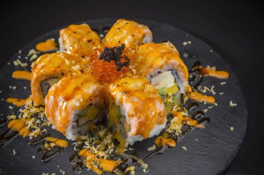 terbiyeli somon havyar ile tepesinde siyah arka plan üzerine siyah plaka üzerinde rulo