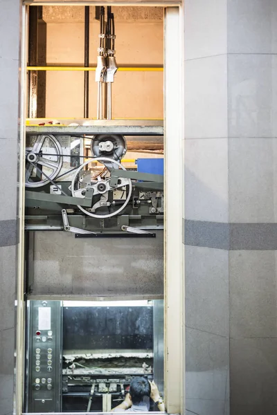 electrician at work adjusting lift with spanners in elevator hoist way