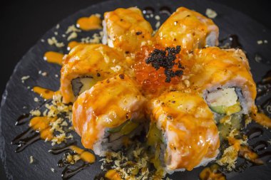 terbiyeli somon havyar ile tepesinde siyah arka plan üzerine siyah plaka üzerinde rulo