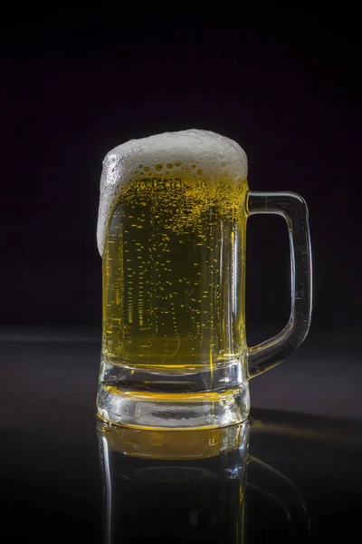 Cold Craft light Beer in a glass with water drops, Mug of beer on black background, Glass of cold light beer with foam, Mug of beer frosty with bubble froth