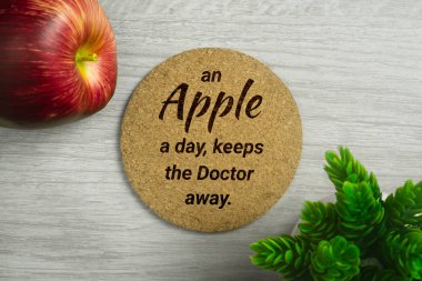 Bir bir elma bir gün uzak doktor tutar. Apple ve Saksı bitki ile ışık ahşap arka plan Cork board.