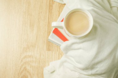 Bir fincan kahve, beyaz kumaş ve ahşap arka plan üzerine kitap yığını. Sabah kahvaltı. Üstten görünüm.