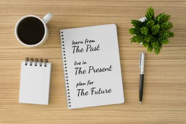 Notebook with motivational and inspirational wisdom quote on wood desk. Learn from the past, live in the present, plan for the future. clipart