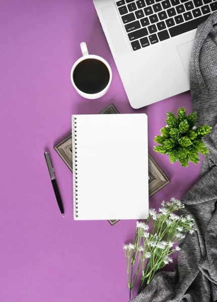 Home work space with notebook, laptop and coffee on pastel violet background. Home office flat lay top view.