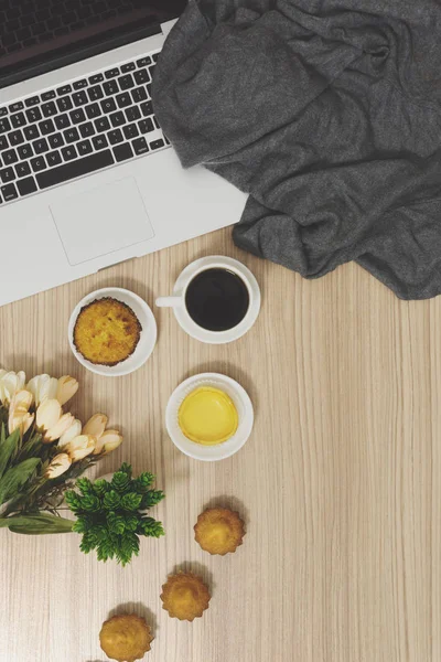 Laptop, cakes and coffee on wood background. Rustic cozy morning breakfast.