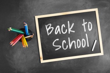 Birden çok renkli renkli kalem kalem tutucu içinde tahtaya yazılan okula dönüş.