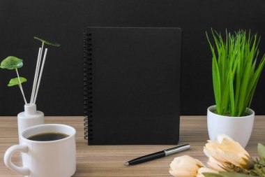 Siyah defter ile kahve fincanı ve siyah arka plan ile ahşap masa üzerinde Saksı bitki. Metin kopya alanı.