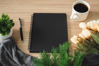 Siyah defter ile kahve fincanı ve çiçek ahşap masa üzerinde. Metin kopya alanı.