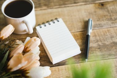 Avuç Taşlama: Not defteri ve rustik ahşap üzerine kahve.