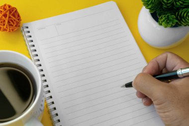 Eli kalem tutan ve defter üzerinde yazma. Metin kopya alanı.