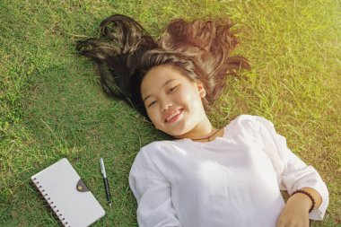 Yalan ve dinlenme sırasında yeşil çimenlerin üzerinde mutlu genç bayan ayarlayın. Üstten görünüm yukarı yüz yalan