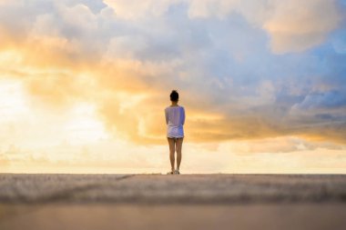 Kadın güzel dramatik bulutlu gökyüzü günbatımı sırasında arıyor.