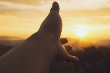 Gün batımında gün batımı manzarasına karşı el.