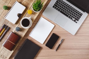 Ofis malzemeleri öğeleri, dizüstü bilgisayar ve kahve rustik ahşap üzerinde. Rustik