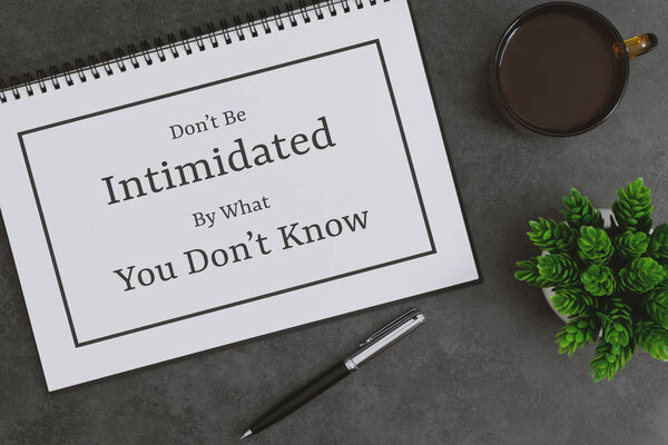 Notebook, pen and coffee cup on dark gray background. Inspirational life quote on notepad.