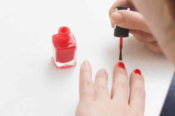 Putting a red varnish on nails on a hand