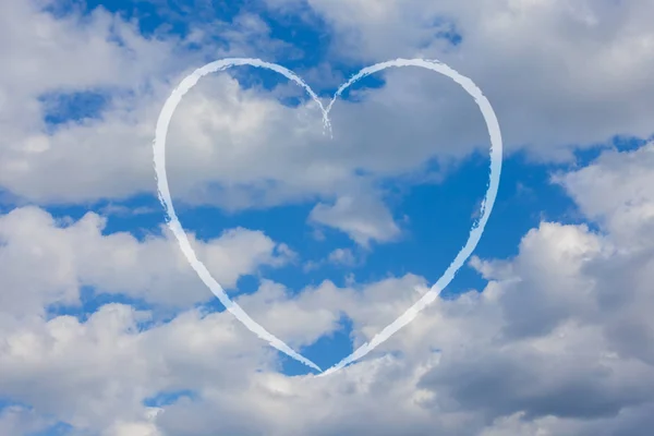 The trace of the plane in the form of heart against the sky with clouds