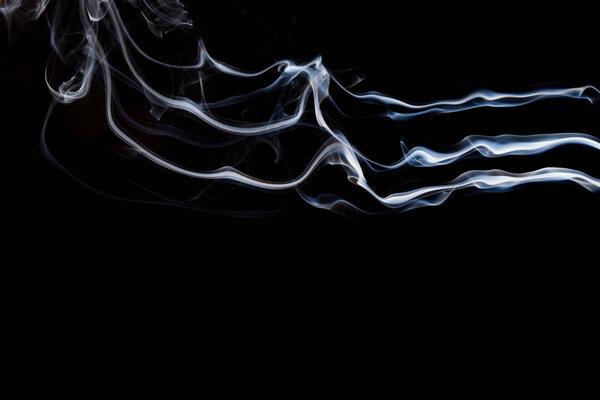 Smoke incense on a black background, abstract photo with swirls in the air