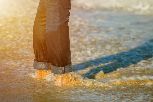 水のビーチで砂の上に立ってのジーンズの女の子 — ストック写真