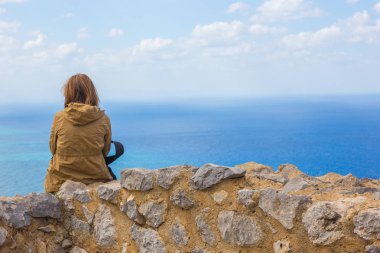 Rüyalar ve deniz karşı bir yükseklikte bağlama La Rocca ve cefalu, Sicilya, İtalya için bir kale kalıntıları oturan turist kız