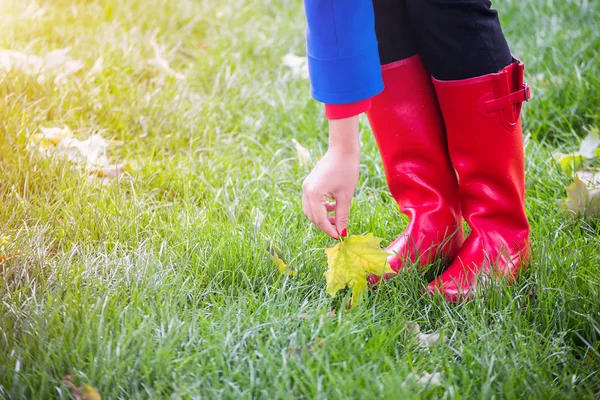 Woman legs in red rubber boots in autumn