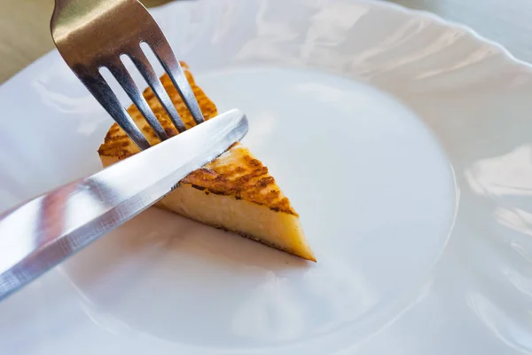 Queso Halloumi a la parrilla en un plato con un cuchillo y tenedor en una re —  Fotos de Stock