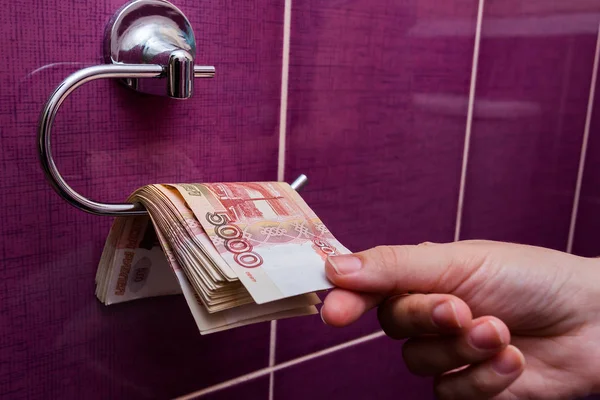 Hand strekt zich uit in het toilet in een stapel bankbiljetten roebels — Stockfoto