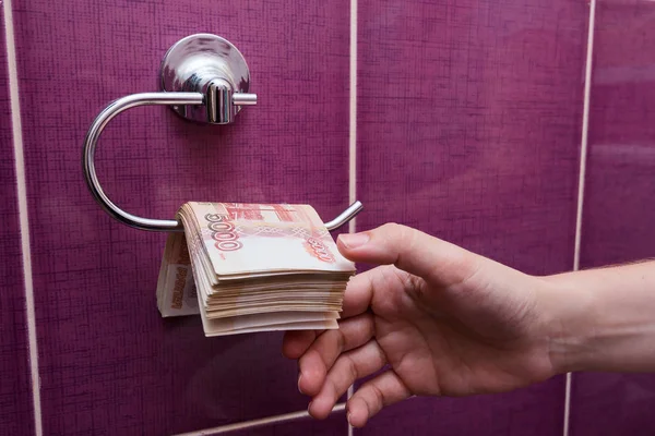 Hand strekt zich uit in het toilet in een stapel bankbiljetten roebels — Stockfoto