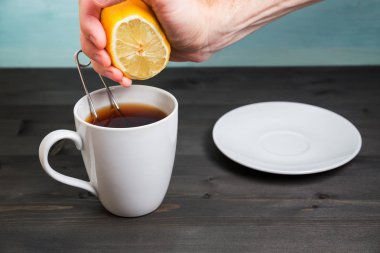 Bir fincan çay içine elinde limon sıkma