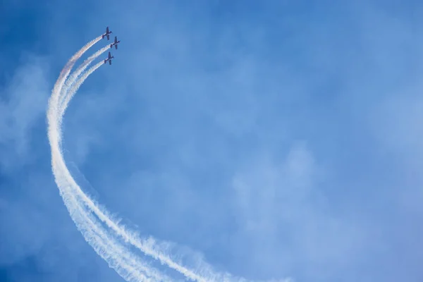 Літак з білим димом на фоні блакитного неба з хмарами — стокове фото