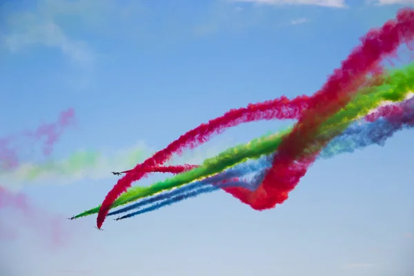 Aircraft with colored smoke trail on the background of blue sky