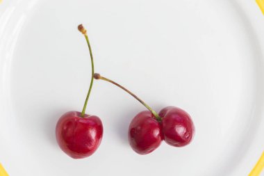 Beyaz bir tabaküzerinde olağandışı mutasyona uğramış kiraz, Gdo ürünleri kavramı, iki erimiş çilek