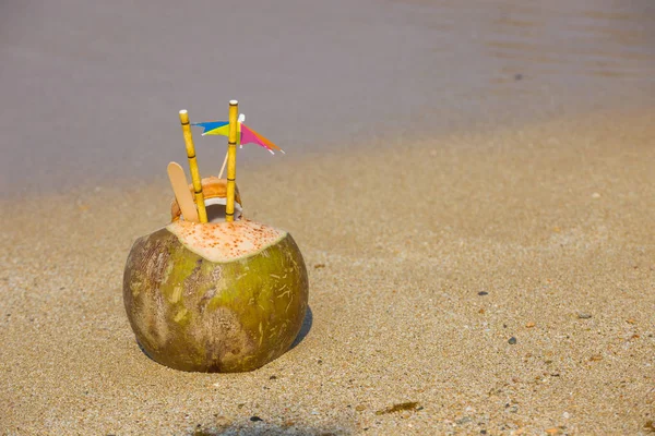 Cocco con ombrellone e tubo sullo sfondo del mare — Foto Stock