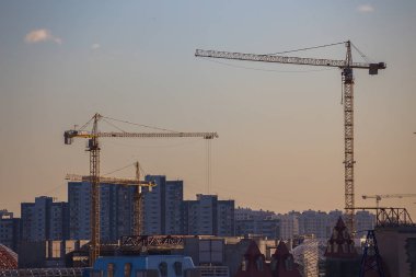 Akşam gökyüzünün arka planında inşaat vinçleri