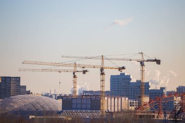 Akşam gökyüzünün arka planında inşaat vinçleri