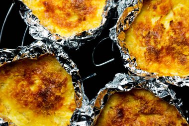 pişmiş pişmiş ezilmiş patates ve peynir ile folyo, siyah arka plan üzerinde yemek  