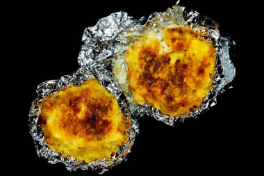 pişmiş pişmiş ezilmiş patates ve peynir ile folyo, siyah arka plan üzerinde yemek  